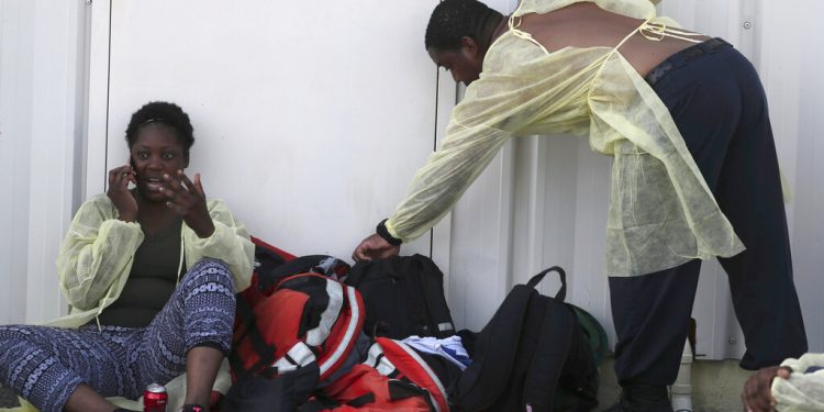 Una mujer (izquierda) habla por su celular tras ser evacuada de las islas Ábaco junto a otras personas luego del paso del huracán Dorian, en un aeropuerto privado en Nassau, Bahamas, el 5 de septiembre de 2019. (AP Foto/Fernando Llano)