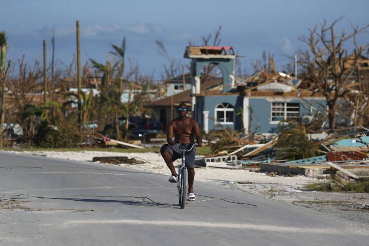 Un hombre pasea en bicicleta entre los escombros provocados por el paso del huracán Dorian, en Marsh Harbor, en la isla de Ábaco, Bahamas, el 6 de septiembre de 2019. (AP Foto/Fernando Llano)