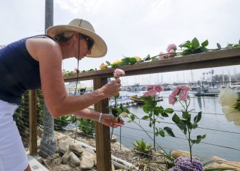 Una mujer deja flores en el exterior del muelle Sea Landing, Santa Barbara, California, en homenaje a las víctimas del incendio en un barco de buceo, el 2 de septiembre de 2019. Foto: Ringo H.W. Chiu / AP.