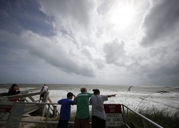 Unas personas observan la marea alta del océano Atlántico previo al posible paso del huracán Dorian, en Vero Beach, Florida, el lunes 2 de septiembre de 2019. (AP Foto/Gerald Herbert)