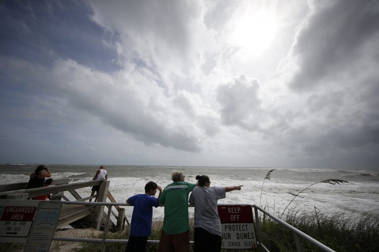 Unas personas observan la marea alta del océano Atlántico previo al posible paso del huracán Dorian, en Vero Beach, Florida, el lunes 2 de septiembre de 2019. (AP Foto/Gerald Herbert)