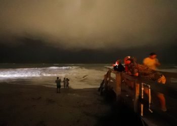 Varias personas caminan por el malecón mientras las bandas exteriores del huracán Dorian llegan a Vero Beach, Florida, la noche del lunes 2 de septiembre de 2019. (Foto AP/Gerald Herbert)