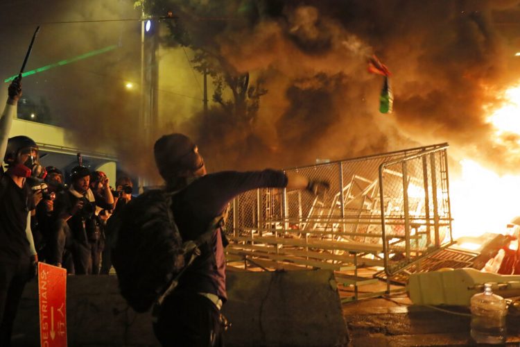 Un manifestante lanza una bomba molotov contra una barrera durante una protesta en Hong Kong, cerca de la sede del gobierno, el sábado 21 de agosto de 2019. (AP Foto/Kin Cheung)