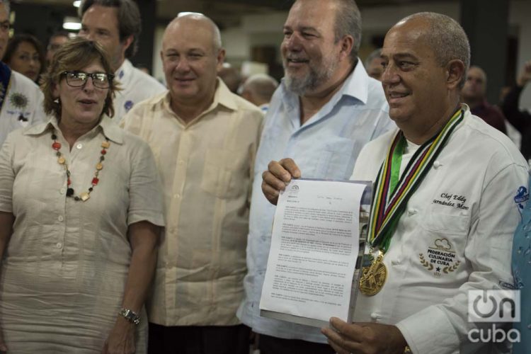 El chef Eddy Fernández (d), presidente de la Federación Culinaria de Cuba, muestra el documento que acredita a la cocina cubana como Patrimonio Cultural de la nación. Junto a él, el ministro de turismo de Cuba, Manuel Marrero (2-d) y Gladys Collazo, presidenta del Consejo Nacional de Patrimonio Cultural (i), entre otras personalidades. Foto: Otmaro Rodríguez.