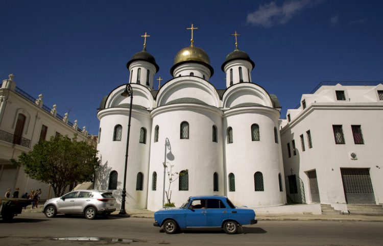 Un auto Moscovich de la era soviética circula por delante de entrada la catedral ortodoxa rusa de La Habana. Foto: Ismael Francisco/AP.