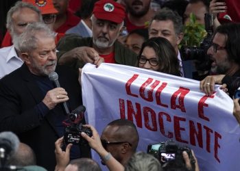 El expresidente de Brasil Luiz Inácio Lula da Silva, sostiene la esquina de una pancarta con la frase (en portugués) "Lula es inocente" mientras se dirige a sus seguidores en el exterior de la sede de la Policía Federal, donde pasó meses encarcelado por cargos de corrupción, en Curitiba, Brasil, el 8 de noviembre de 2019. Foto: Leo Correa / AP / Archivo.