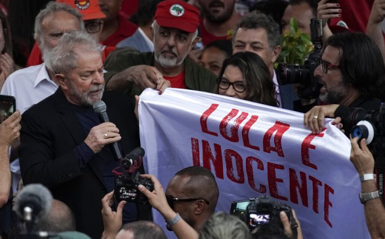 El expresidente de Brasil Luiz Inácio Lula da Silva, sostiene la esquina de una pancarta con la frase (en portugués) "Lula es inocente" mientras se dirige a sus seguidores en el exterior de la sede de la Policía Federal, donde pasó meses encarcelado por cargos de corrupción, en Curitiba, Brasil, el 8 de noviembre de 2019. Foto: Leo Correa / AP / Archivo.