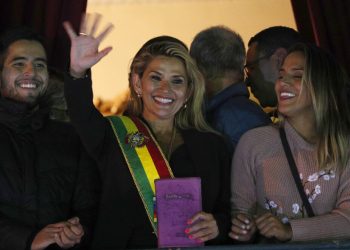 La segunda vicepresidenta del Senado de Bolivia y senadora de la oposición Jeanine Áñez, en el centro, saluda a la multitud ataviada con la banda presidencial en el balcón del palacio de Quemado, tras proclamarse presidenta interina del país, en la Paz, Bolivia, el martes 12 de noviembre de 2019. Foto: Juan Karita / AP.