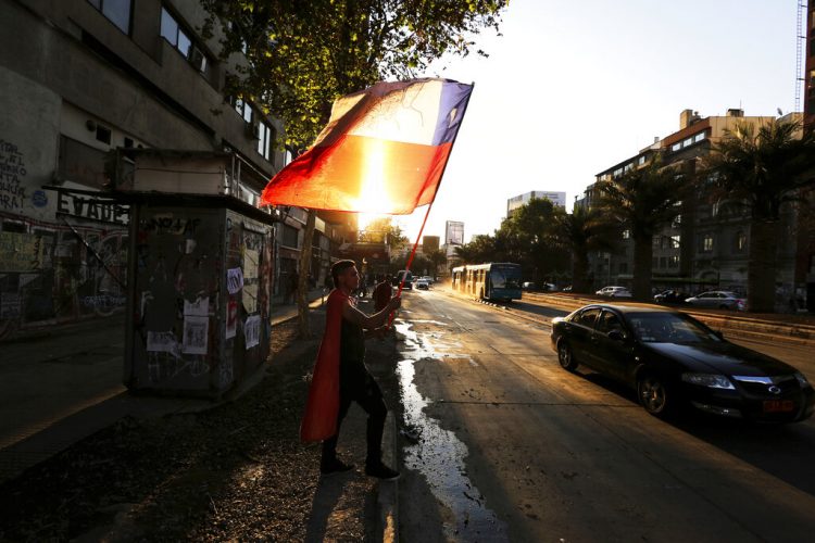 Un manifestante contra el gobierno ondea una bandera chilena durante una protesta en Santiago de Chile el lunes 16 de diciembre de 2019. Foto: Fernando Llano / AP.