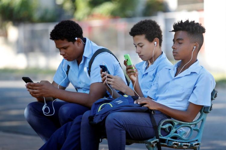 Un grupo de estudiantes usa su teléfono celular en un parque de La Habana. EFE/ Yander Zamora