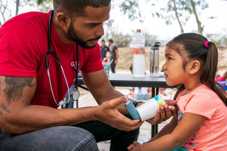 El médico cubano Dairon Elisondo trata a una niña de 4 años, enferma de asma, en un campamento de migrantes en Matamoros, México. Foto: Ilana Panich-Linsman / The New York Times.