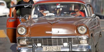 Un grupo de personas suben a un automóvil clásico que funciona como taxi en La Habana (Cuba). Foto: EFE/ Yander Zamora