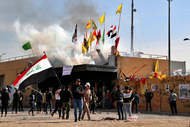 Milicianos proiraníes y sus partidarios provocan un incendio mientras soldados estadounidenses lanzan gases lacrimógenos en la embajada de Estados Unidos en Bagdad el 1 de enero de 2020. Foto: Khalid Mohammed/AP.