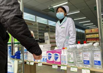 Una farmacéutica atiende a clientes en la entrada de una tienda en Beijing, China, el 20 de febrero de 2020. Foto: Ng Han Guan / AP.