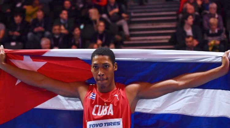 Cuba's Juan Miguel Echevarria celebrates with his flag after winning the men's long jump final event at the 2018 IAAF World Indoor Athletics Championships at the Arena in Birmingham on March 2, 2018. / AFP PHOTO / Ben STANSALL