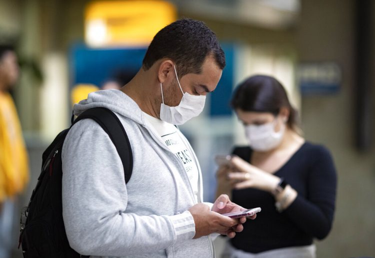 Pasajeros usando mascarillas como precaución contra el contagio del nuevo coronavirus usan sus teléfonos en el Aeropuerto Internacional de Sao Paulo, Brasil, el jueves 27 de febrero de 2020. Foto: Andre Penner / AP.