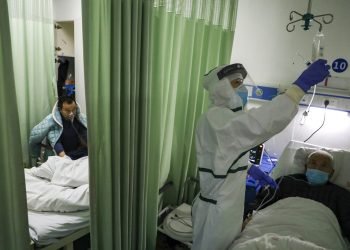 Una enfermera comprueba el estado de un paciente en un ala de aislamiento para pacientes del coronavirus 2019-nCoV en un hospital de Wuhan, en la provincia china de Hubei. Foto: Chinatopix vía AP.