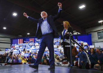 El precandidato presidencial demócrata y senador Bernie Sanders, acompañado por su esposa, Jane O'Meara Sanders, levanta los brazos durante una reunión proselitista en Essex Junction, Vermont, la noche del martes 3 de marzo de 2020. Foto: AP/Matt Rourke.