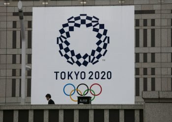 Un hombre pasa junto a un gran cartel promocionando los Juegos Olímpicos de Tokio 2020 en Tokio, marzo de 2020. Foto: AP/Jae C. Hong/Archivo.