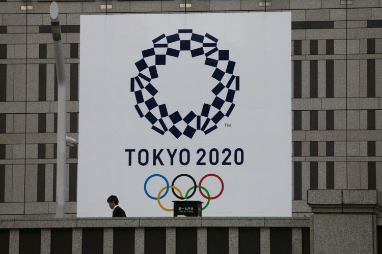 Un hombre pasa junto a un gran cartel promocionando los Juegos Olímpicos de Tokio 2020 en Tokio, marzo de 2020. Foto: AP/Jae C. Hong/Archivo.