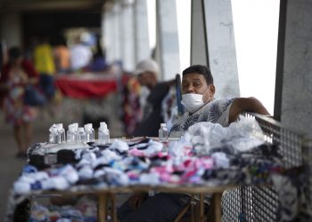 Un vendedor ambulante vende alcohol y máscaras faciales para protegerse contra la propagación del nuevo coronavirus en una estación de tren en Río de Janeiro, Brasil, el lunes 16 de marzo de 2020. (Foto AP/Silvia Izquierdo)