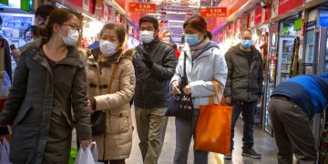 Varias personas con mascarillas compran en un mercado en Beijing, el 14 de marzo de 2020. Foto: AP/Mark Schiefelbein.