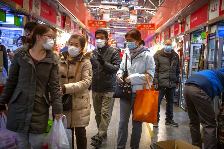 Varias personas con mascarillas compran en un mercado en Beijing, el 14 de marzo de 2020. Foto: AP/Mark Schiefelbein.