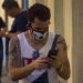 Un cubano revisa su celular usando un nasobuco en La Habana, como medida de protección frente a la pandemia de COVID-19. Foto: Otmaro Rodríguez.