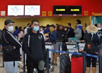 Varias personas esperan la salida de sus vuelos antes del cierre parcial de las fronteras cubanas para evitar la propagación de la COVID-19, en el Aeropuerto Internacional "José Martí" de La Habana, el 23 de marzo de 2020. Foto: Yander Zamora / EFE.