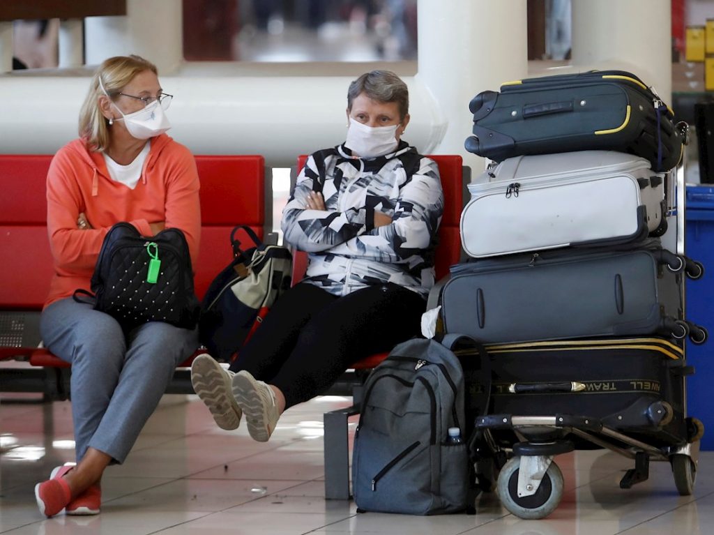 Personas esperan la salida de sus vuelos antes del cierre parcial de las fronteras cubanas para evitar la propagación de la COVID-19, en el Aeropuerto Internacional "José Martí" de La Habana, el 23 de marzo de 2020. Foto: Yander Zamora / EFE.