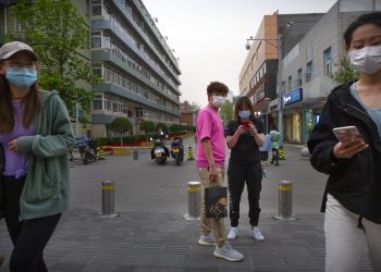 Varias personas cubren sus caras con máscaras como medida contra la propagación del nuevo coronavirus mientras caminan al aire libre por una zona comercial en Beijing, el viernes 24 de abril de 2020.  (AP Foto/Mark Schiefelbein)