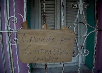 Un cartel de "Cerrado por coronavirus COVID-19" cuelga de la puerta de rejas de un negocio en La Habana, Cuba, el viernes 24 de abril de 2020. (AP Foto/Ismael Francisco)