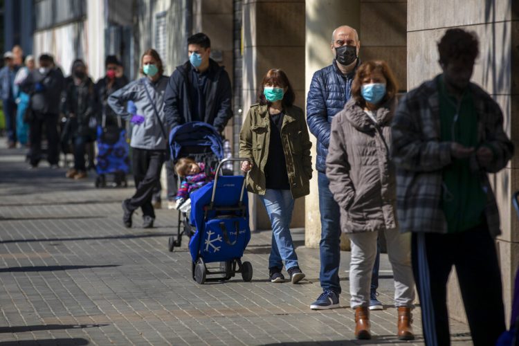 Personas con mascarillas hacen cola en una tienda de Barcelona. Foto: Emilio Morenatti/AP.