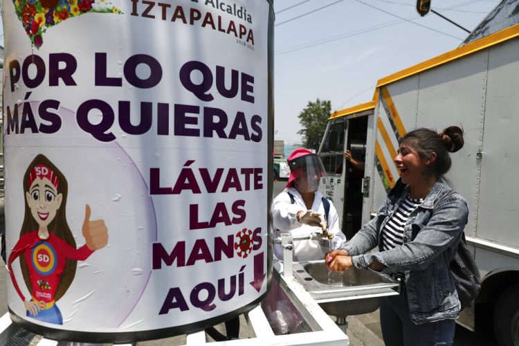 Una trabajadora municipal con equipo protector invita a una ciudadana a lavarse las manos en un lavabo portátil en la Ciudad de México el miércoles 22 de abril de 2020.  Foto: Eduardo Verdugo/AP.