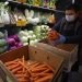 Un empeado luciendo una máscara protectora y guantes contra el COVID-19, coloca zanahorias en los estantes en el Gus's Community Market el viernes, 27 de marzo del 2020, en San Francisco.  (AP Foto/Ben Margot)