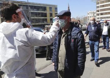 Un empleado de un supermercado le toma la temperatura a los clientes en Ankara, Turquía, el 17 de abril del 2020. (AP Photo)