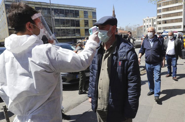 Un empleado de un supermercado le toma la temperatura a los clientes en Ankara, Turquía, el 17 de abril del 2020. (AP Photo)