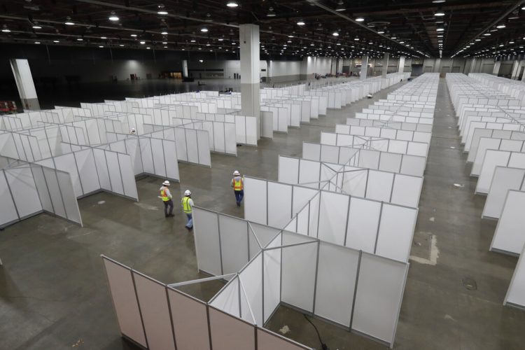 Trabajadores supervisan la instalación de cuartos de hospital temporales en el centro de convenciones TCF Center, en Detroit.  Foto: AP/Carlos Osorio.