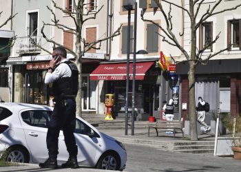 Un policía llama por celular después de que un hombre con un cuchillo atacara a residentes que salieron de compras en una población sometida a cuarentena el sábado 4 de abril de 2020 en Romans-sur-Isere, en el sur de Francia. Foto: AP.