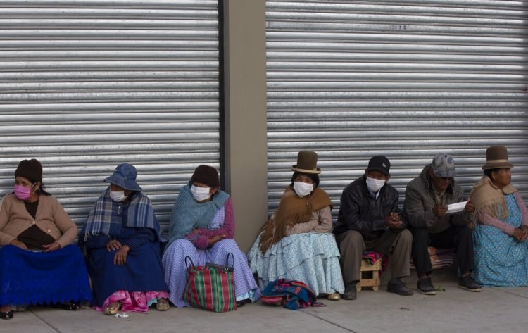 Ancianos, en su mayoria con mascarillas, esperan en fila a recibir su pensión mensual en La Paz, Bolivia, el jueves 9 de abril de 2020. Foto: Juan Karita/AP.