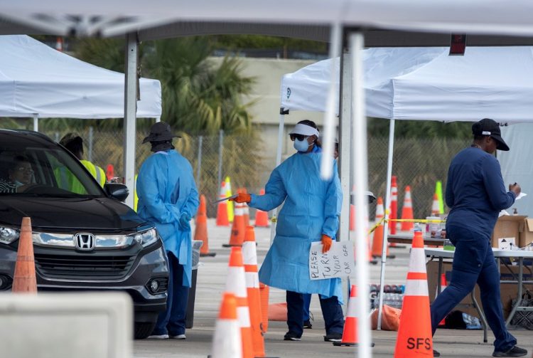 Los miembros de la Guardia Nacional usan equipo de protección mientras conducen hisopos nasales para pruebas de coronavirus en una ubicación de prueba en el estacionamiento del estadio Super Bowl de Hard Rock Cafe Miami, en Miami. Foto: Cristóbal Herrera/EFE/EPA.