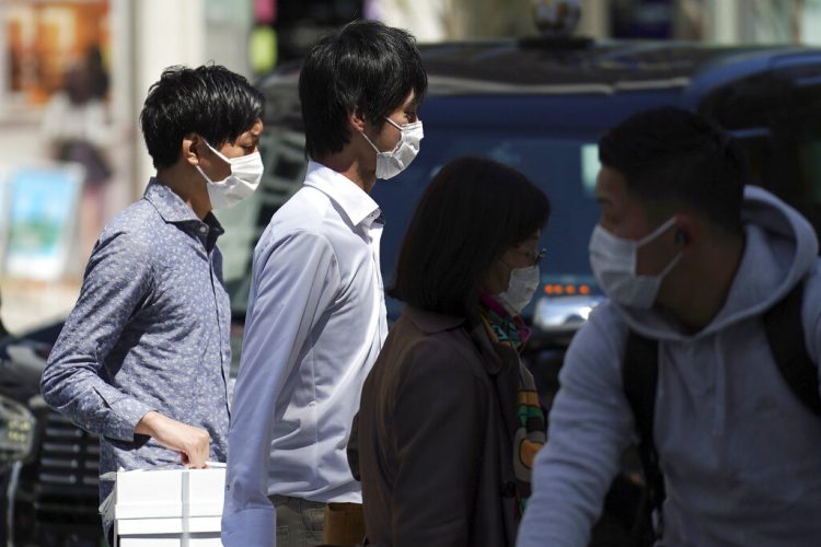 Varias personas, con mascarilla para ayudar a frenar la propagación del coronavirus, cruzan un paso de peatones, en Tokio, Japón, el 10 de abril de 2020. (AP Foto/Eugene Hoshiko)