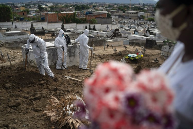 Trabajadores de un cementerio, vestidos con trajes de protección, cierran la tumba de Ana María, una ayudante de enfermería de 56 años que falleció a causa del coronavirus, en Río de Janeiro, Brasil, el 28 de abril de 2020.  Foto: AP/Leo Correa.