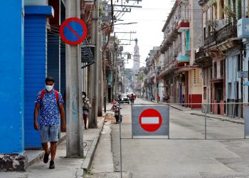 Un hombre con tapabocas pasa por una calle con acceso restringido por la Covid-19 en La Habana. Foto: Ernesto Mastrascusa / EFE.