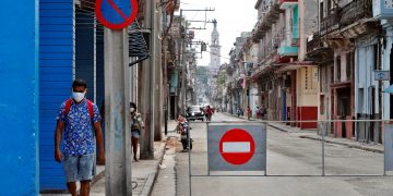 Un hombre con tapabocas pasa por una calle con acceso restringido por la Covid-19 en La Habana. Foto: Ernesto Mastrascusa / EFE.
