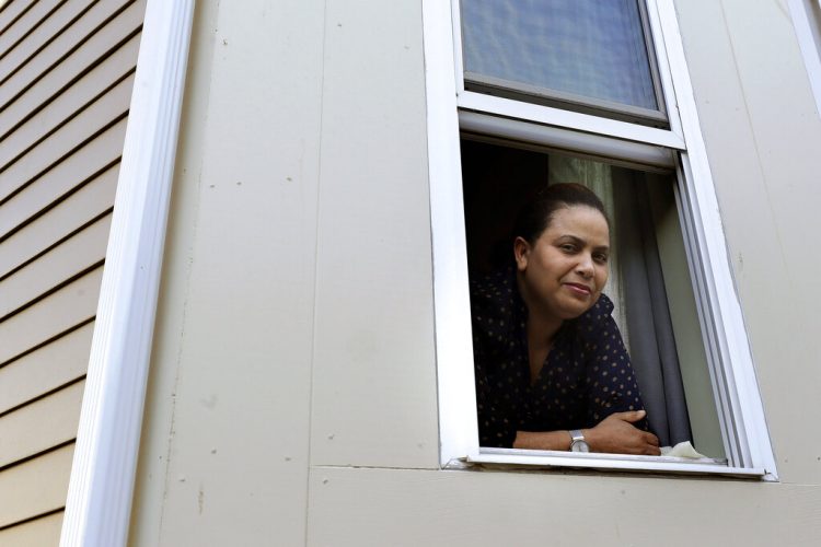 En imagen del miércoles 20 de mayo de 2020, Wendy De Los Santos, originaria de la República Dominicana, posa para una fotografía desde una ventana de su hogar, en Malden, Massachusetts. (AP Foto/Steven Senne)