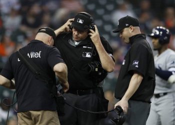 Esta foto del 5 de junio muestra a los árbitros Paul Emmel (centro) y Mike Estabrook, quienes esperan por la revisión de una jugada durante el juego entre los Tigres de Detroit y los Rays de Tampa. (AP Foto/Carlos Osorio)