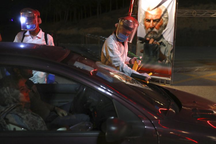 Trabajadores con trajes protectores desinfectan autos que entran a un autocine situado junto a la torre Milad, en Teherán, el viernes 1 de mayo del 2020. Irán es el epicentro de la pandemia del Covid-19 en la región. Foto: AP/Vahid Salemi.