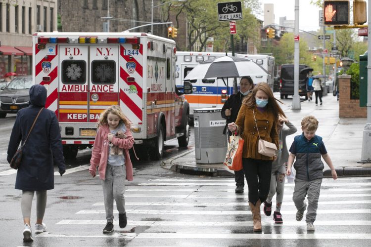 Varias personas, entre ellas niños, caminan frente al NewYork–Presbyterian Brooklyn Methodist Hospital en la ciudad de Nueva York, el 6 de mayo del 2020. Foto: Mark Lennihan / AP.