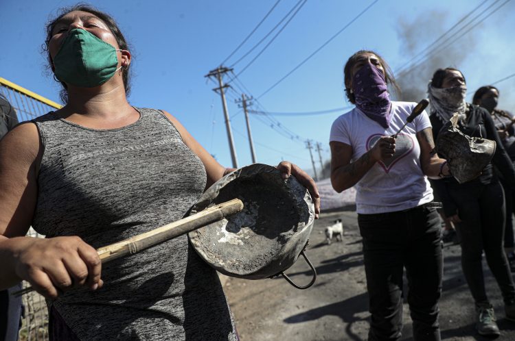 Manifestantes reunidas cerca de una barricada en llamas, durante una protesta pidiendo más ayuda alimentaria del gobierno en la pandemia del coronavirus, en un vecindario de Santiago de Chile, el martes 26 de mayo de 2020.  Foto: Esteban Félix/AP